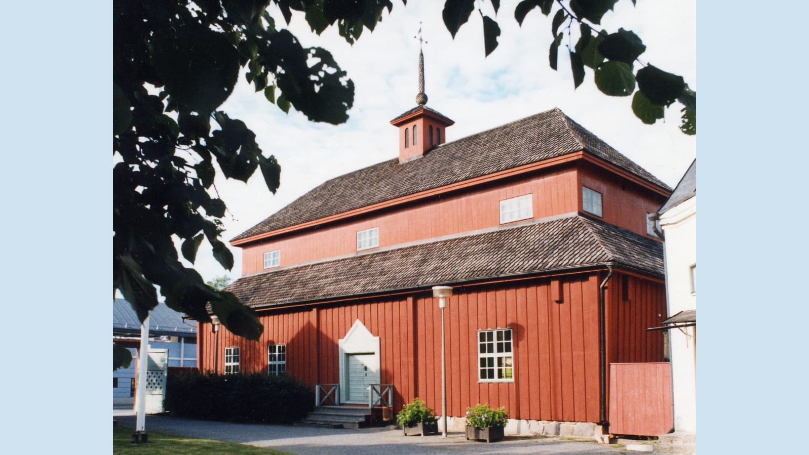 Punainen, puinen vanha koulurakennus kesällä kuvattuna.