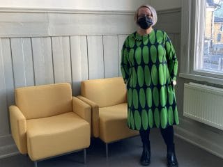 Naisen yllä vihreäkuvioinen trikoomekko.