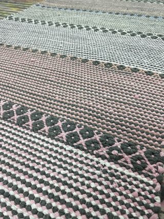 Vaaleanpuna-harmaa raitainen matto.