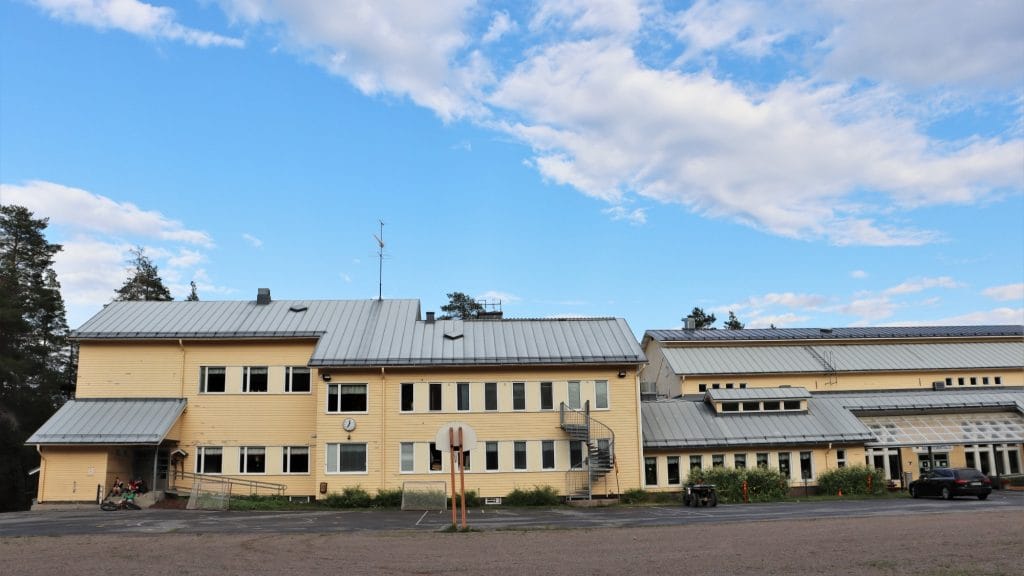 vaaleankeltainen koulu- ja monitoimitalorakennus, sininen poutapilvitaivas
