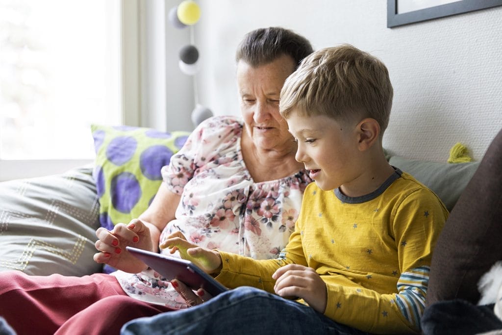 Grandmother reading from a tablet device with a boy.